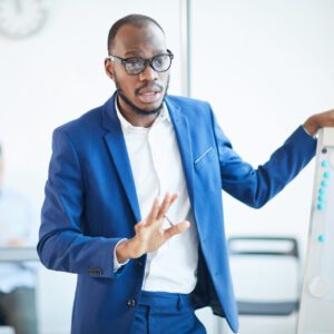 Waist up portrait of successful African-American businessman standing by whiteboard while presenting design project during meeting in office, copy pace